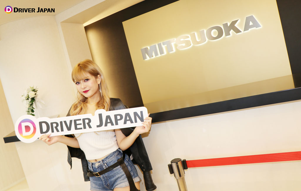 光岡自動車の東京ショールームにあるMITUOKAロゴの看板と記念撮影をするSUMIKA