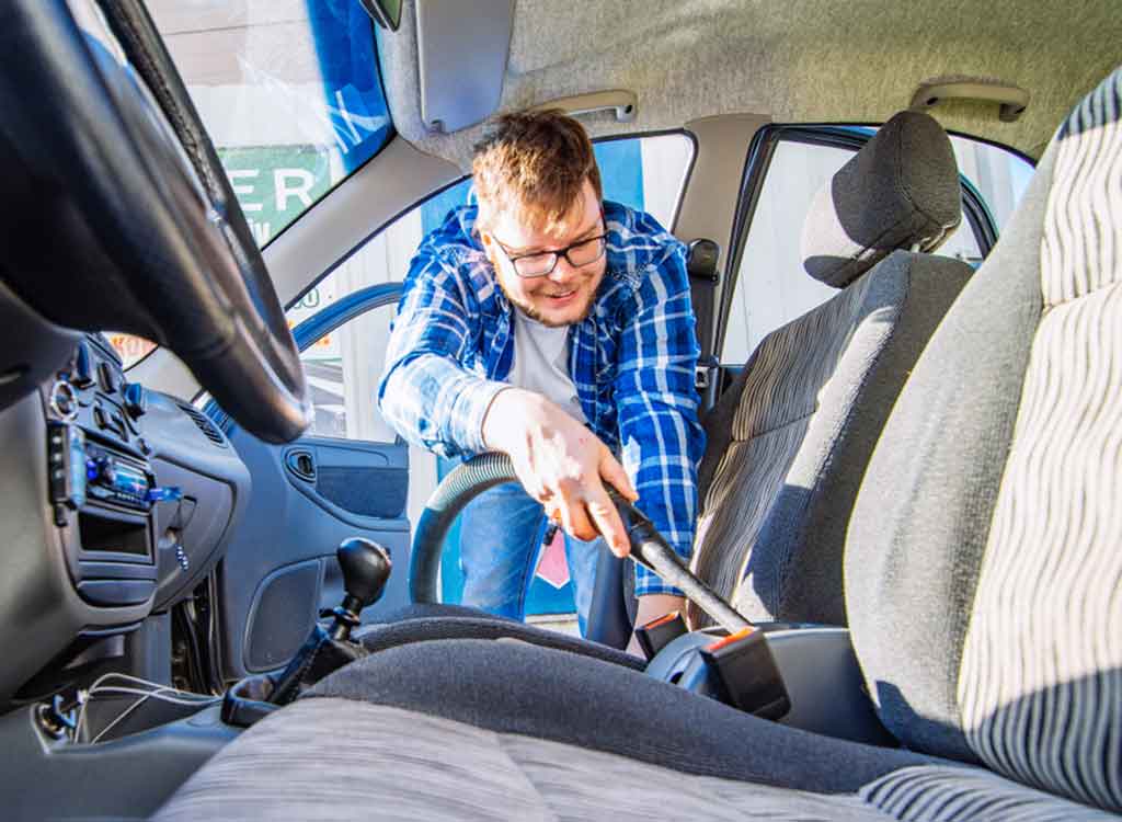シートのシミを掃除機で吸引する男性