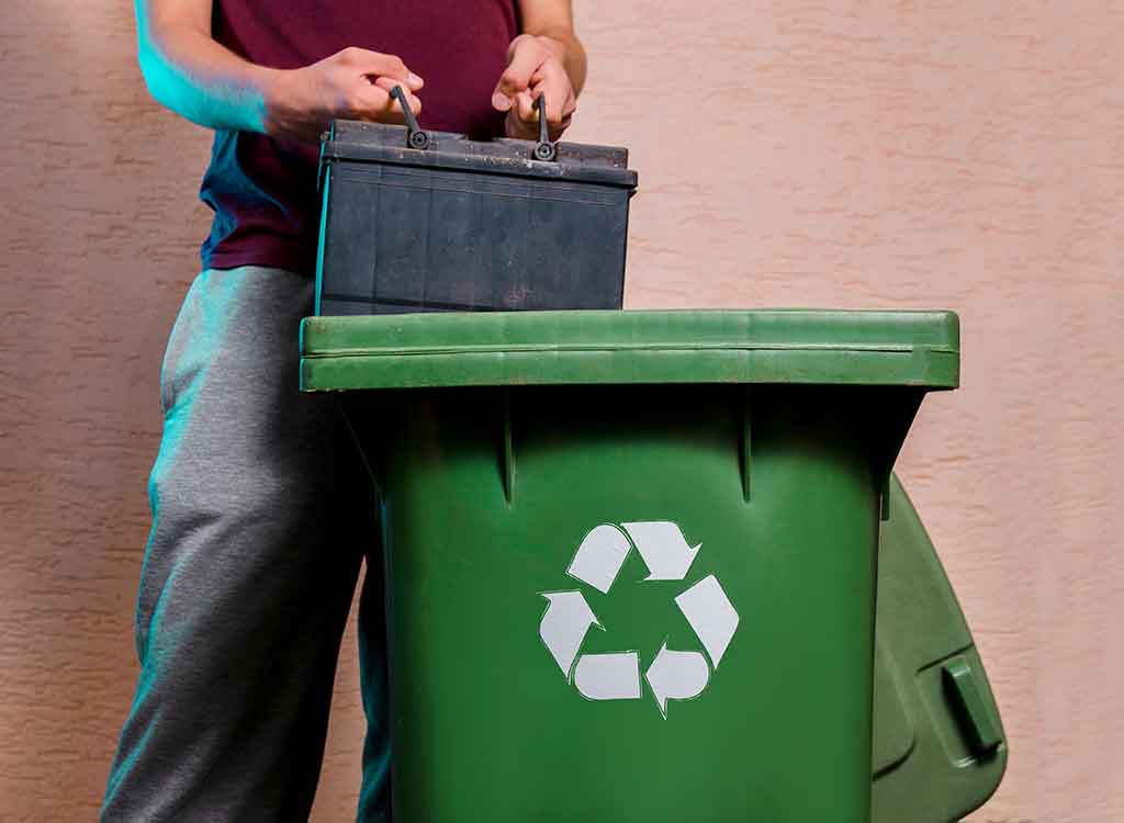 古い車のバッテリーをゴミ箱へ捨てる様子