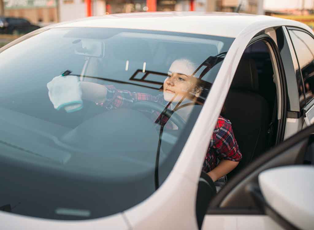 フロントガラスの内側を掃除する女性