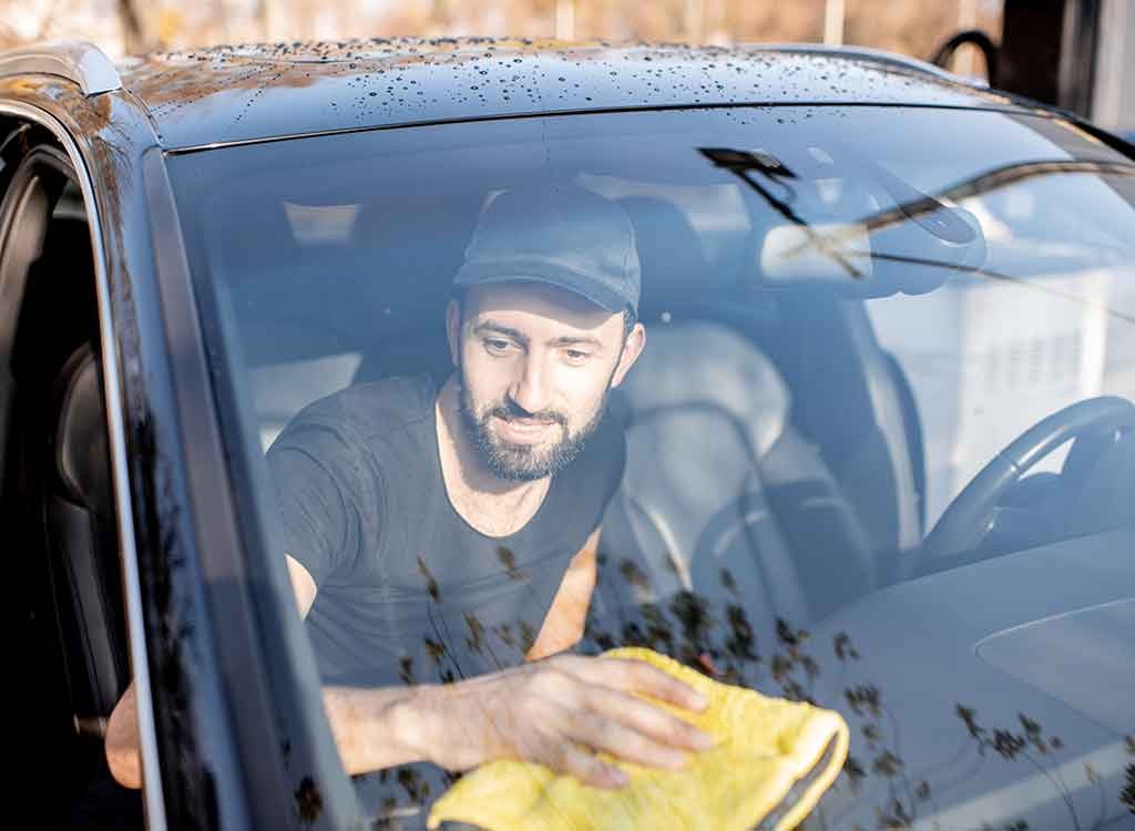 フロントガラスの内側を掃除する男性