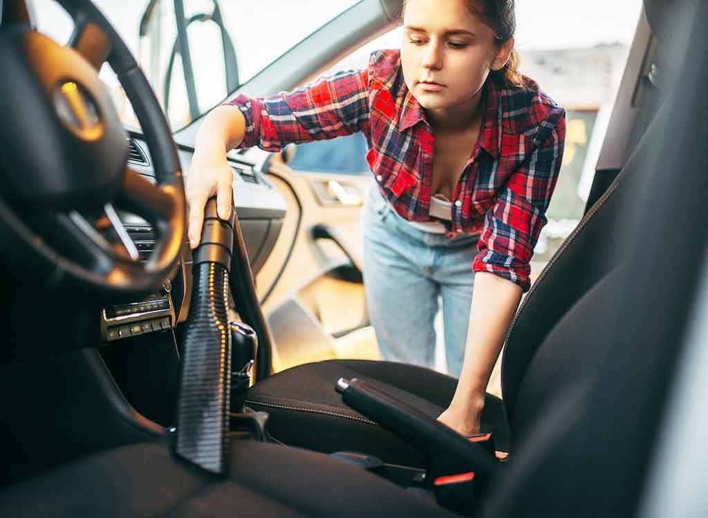 掃除機で助手席のシートを掃除する女性