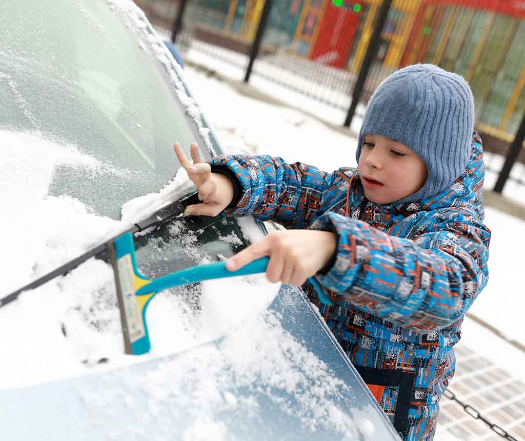 凍った車のフロントガラスを取り除く子ども