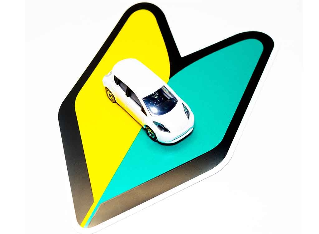 若葉マークの上に乗った白い車