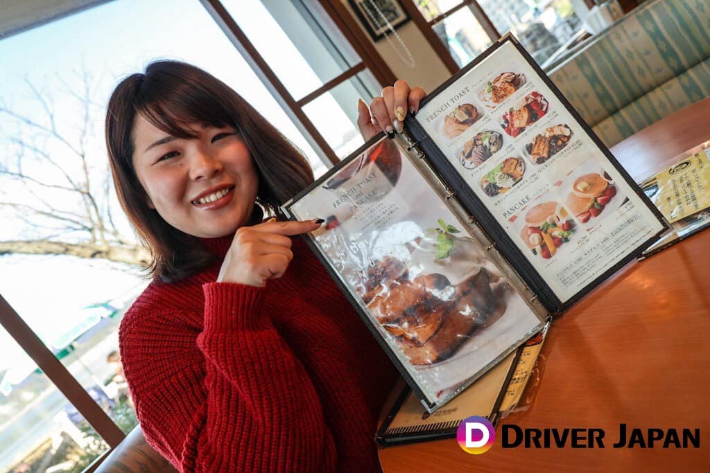 なぎさ橋珈琲のメニューを持っているあっこ