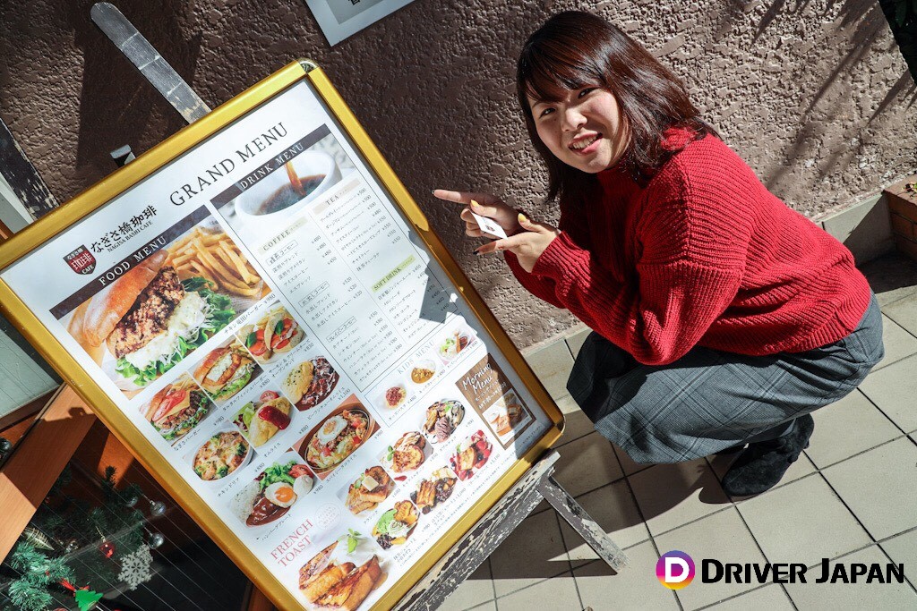 なぎさ橋珈琲　外にあるメニューを指さすあっこ