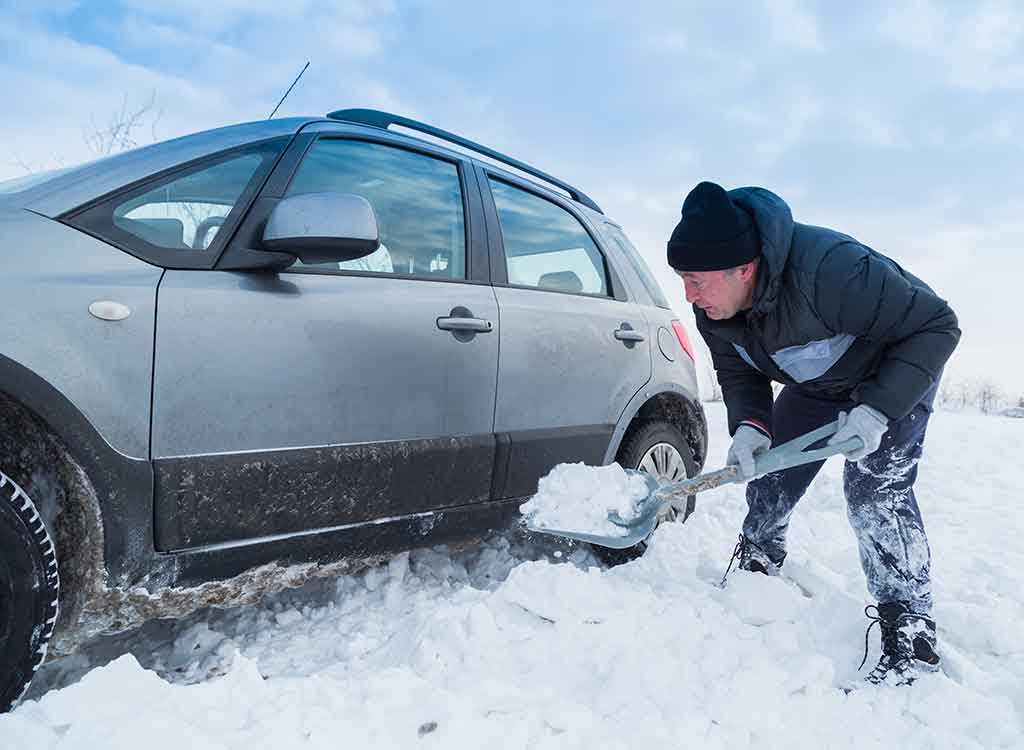 車の横に雪を溜める男性