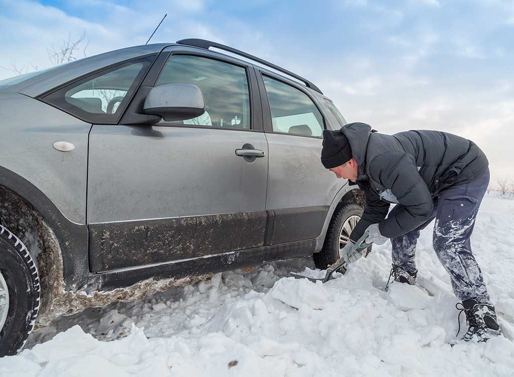 車の周囲の雪をスコップでかき出す男性