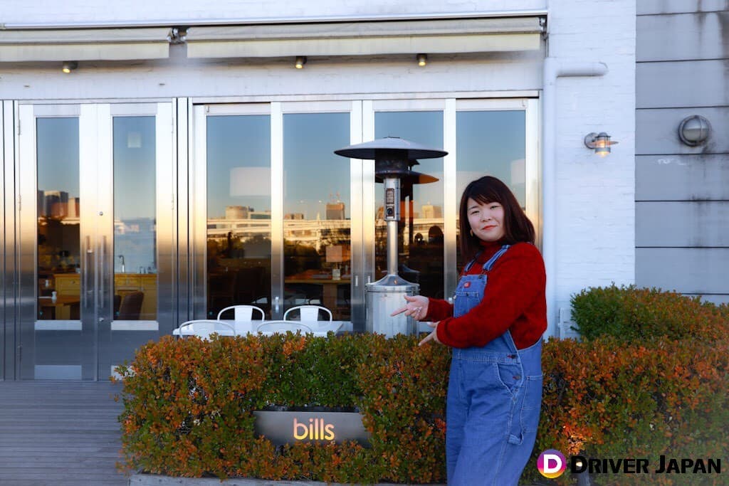 billsの看板前に立つあっこ